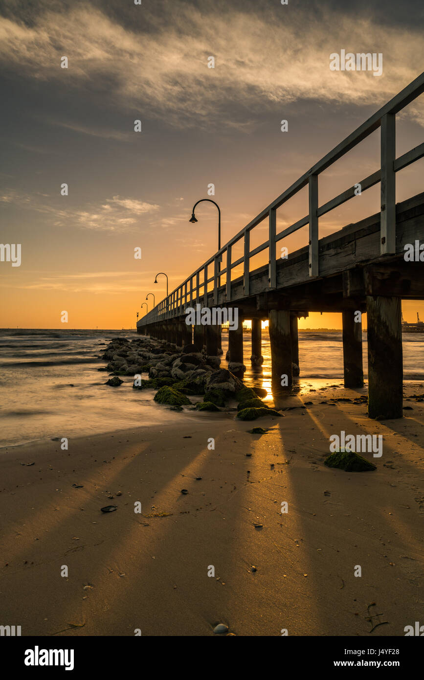 Ein Pier in Port Melbourne, Melbourne, Victoria, führt Australia.The Pier diagonal die Augen bis zum Horizont mit einem Sonnenuntergang geben eine Orange/goldene Farbton Stockfoto