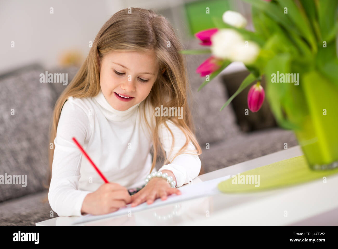 Schöne glückliche kleine Mädchen schreiben zu Hause - Bildung, Bildung, Schule, Muttertag und Konzept Stockfoto