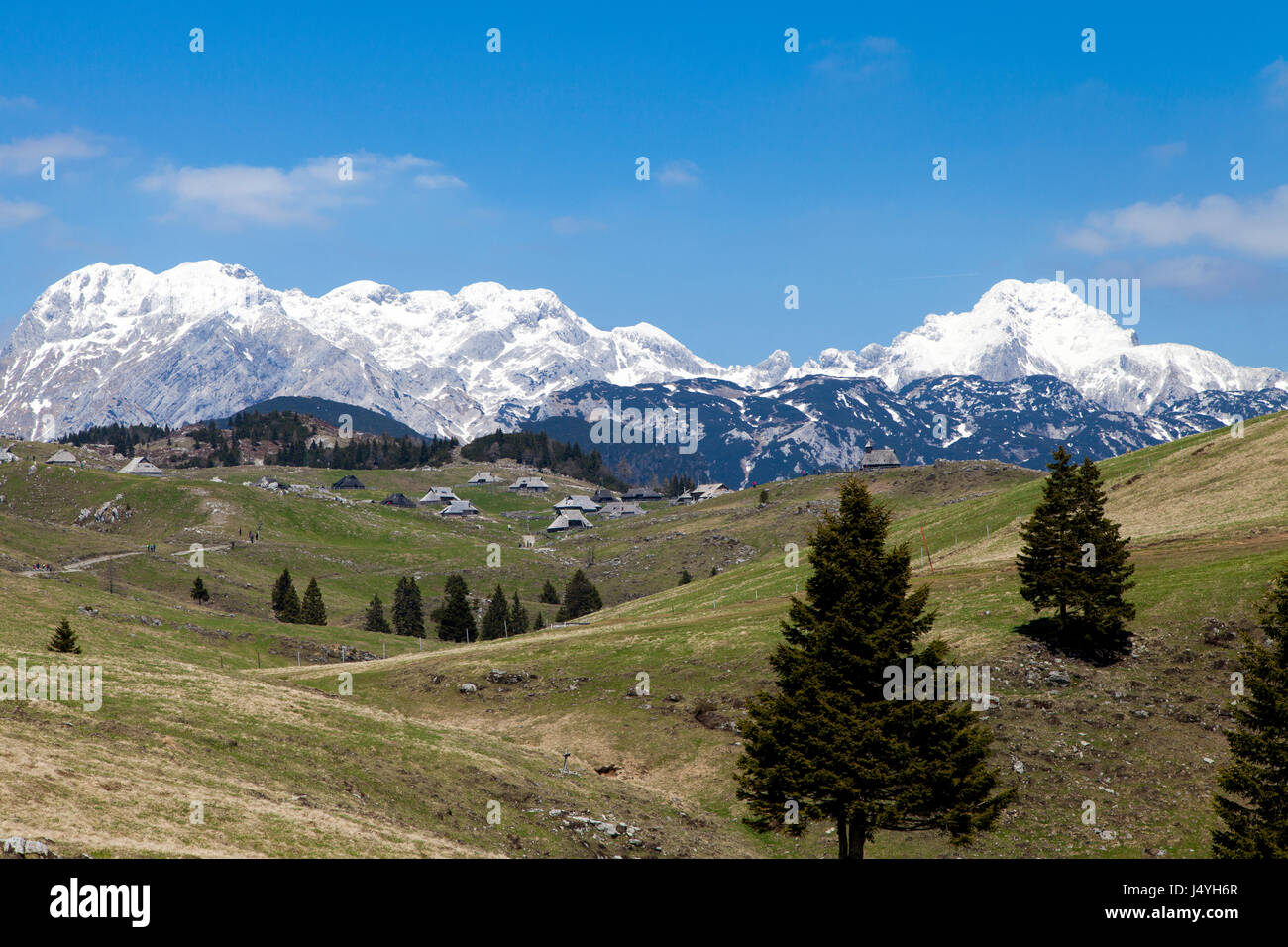 Schöne Aussicht auf Hirte Dorf, Tableland Velika Planina in Slowenien, vor blauem Himmel und hohen Bergen mit Schnee bedeckt. Platz für text Stockfoto