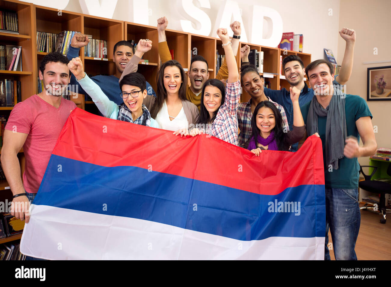 Glückliche Gruppe von Studenten aus Serbien mit erhöhten Sieg Fäusten, präsentiert ihr Land mit Flagge Stockfoto