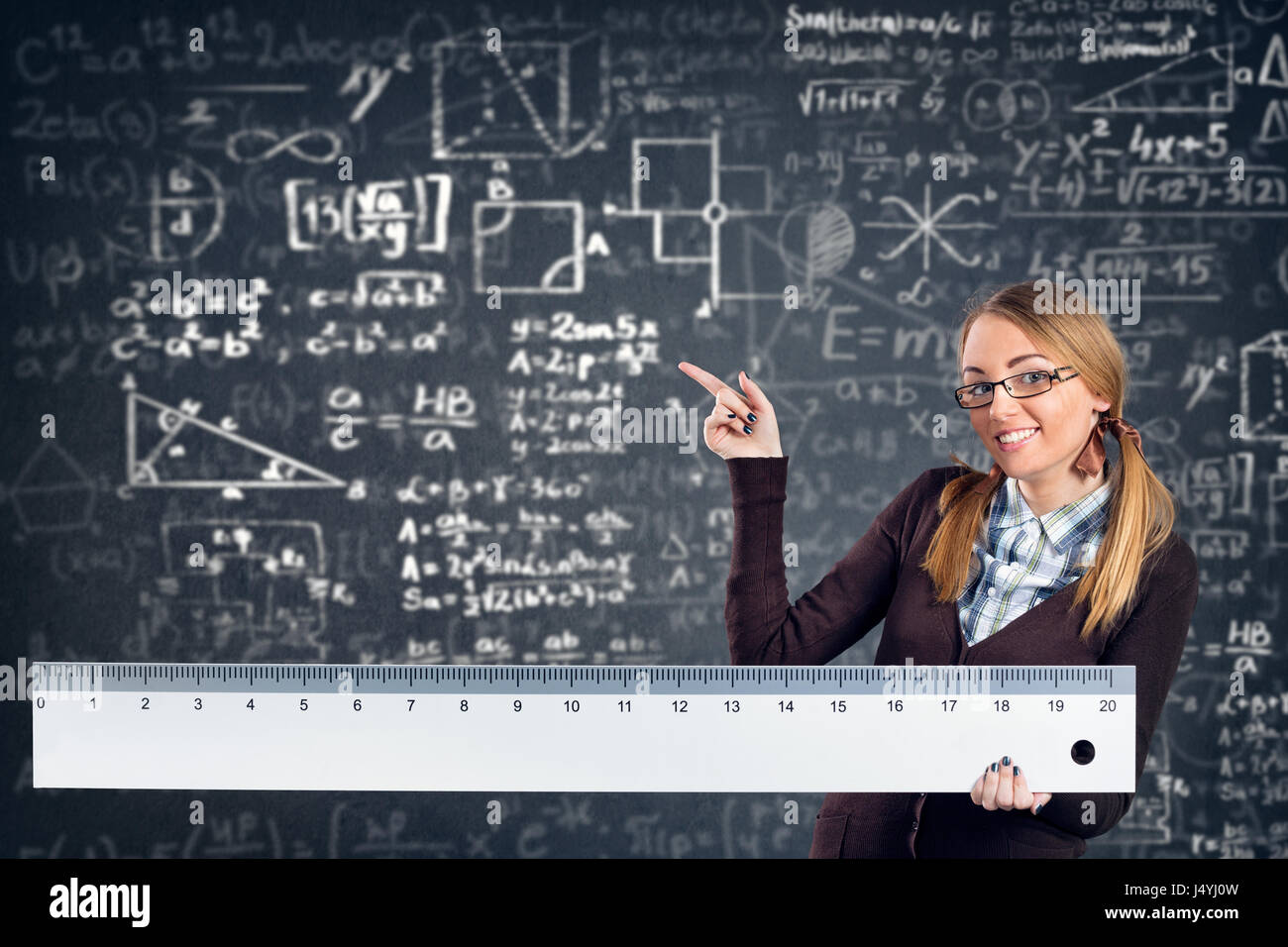 lächelnde Studentin mit einem großen Lineal zeigt Formeln auf Hintergrund Stockfoto