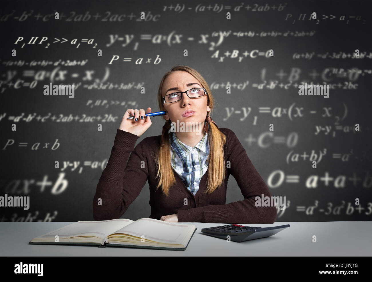 Junge Studentin mit nachdenklichen Ausdruck sitzen an einem Schreibtisch mit mathematischen Formeln über den Kopf Stockfoto