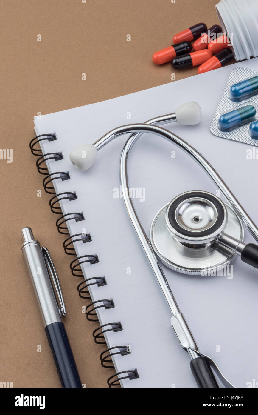 Stethoskop, Tabletten, Ampullen im Arztzimmer auf braunem Hintergrund Draufsicht mockup Stockfoto