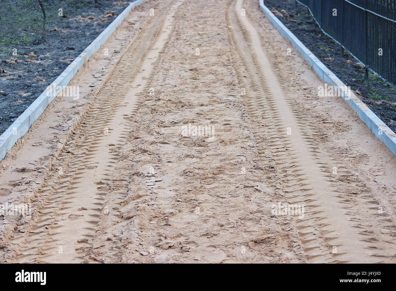 Sand als Basis vor der Verlegung Pflastersteine, verstreut durch Arbeiter mit Schaufeln und verstopft mit einem vibroroller Stockfoto