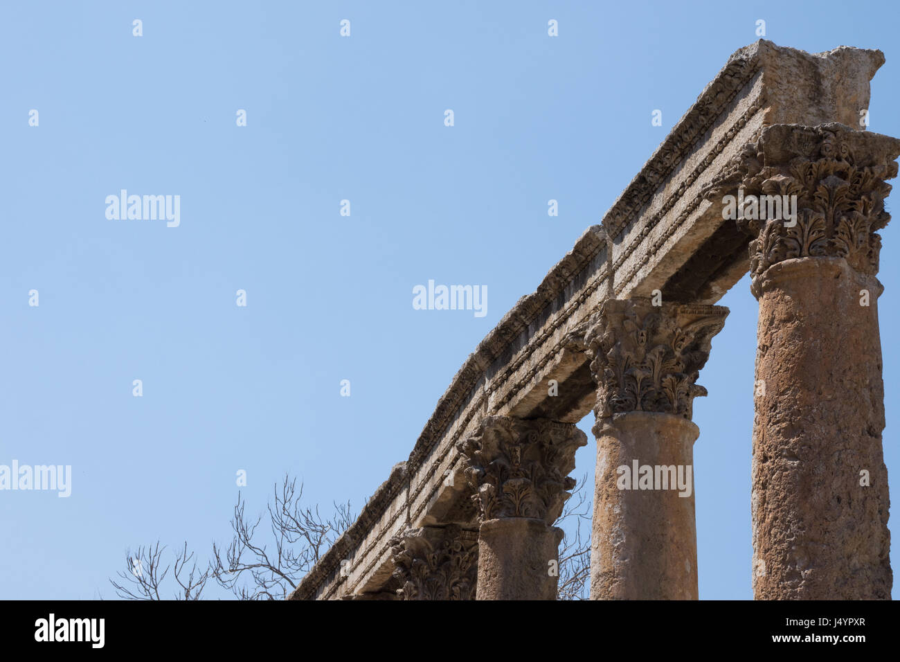 Reihe von Steinsäulen, garniert mit kunstvoll geschnitzten Kapitellen und steinernen Türsturz oder Balken. Alte Ruinen befinden sich in Amman Jordanien und haben blaue Himmel Stockfoto