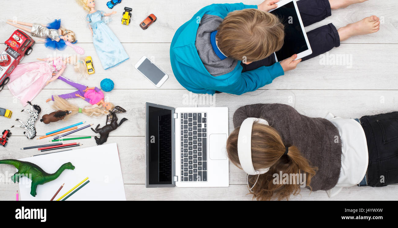 zwei verwöhnte Kinder auf ihrem Ipad und laptop Stockfoto