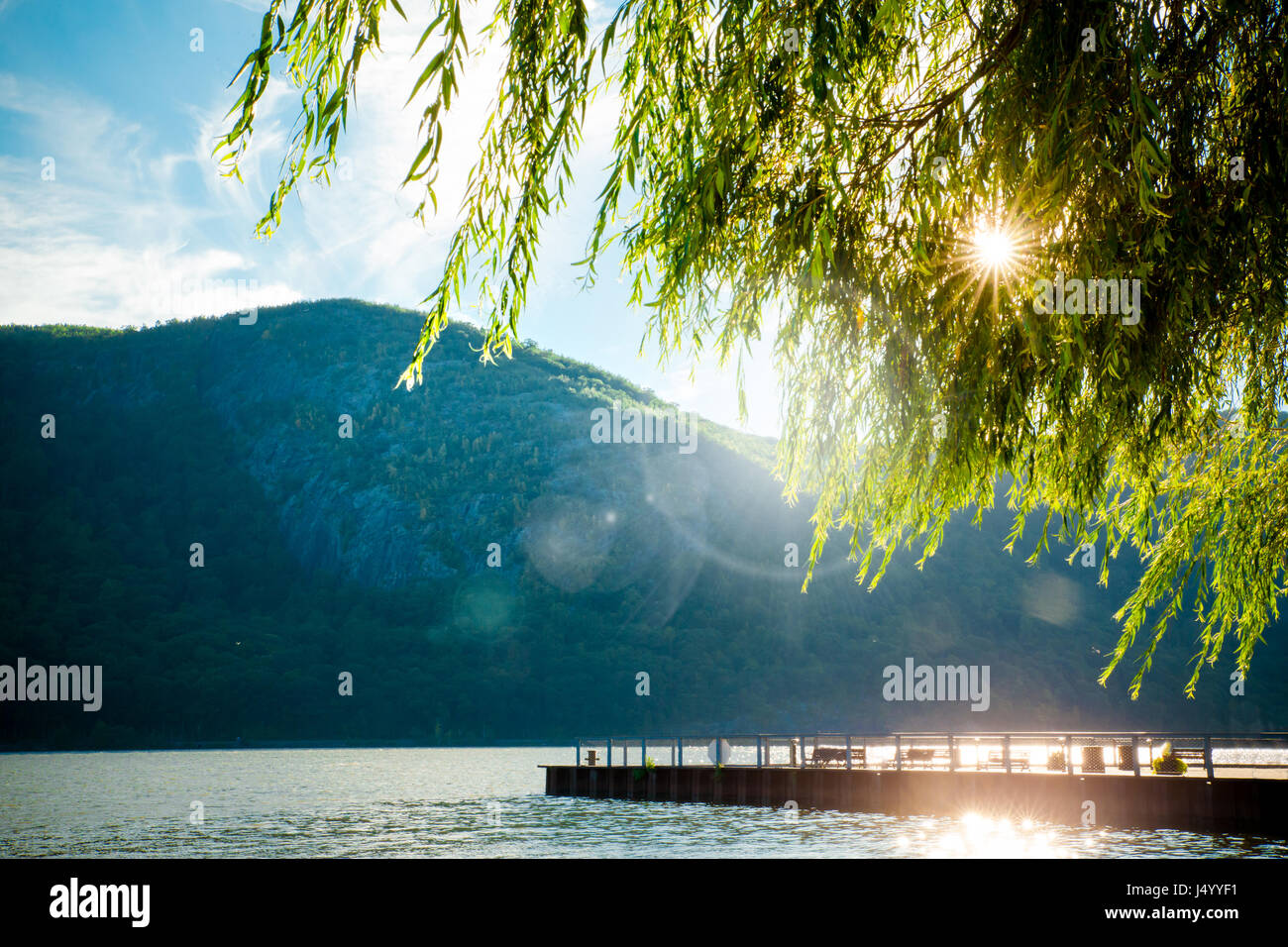 Fluss, Berge und Dock mit Sonne durch die Bäume von Cold Spring NY Stockfoto