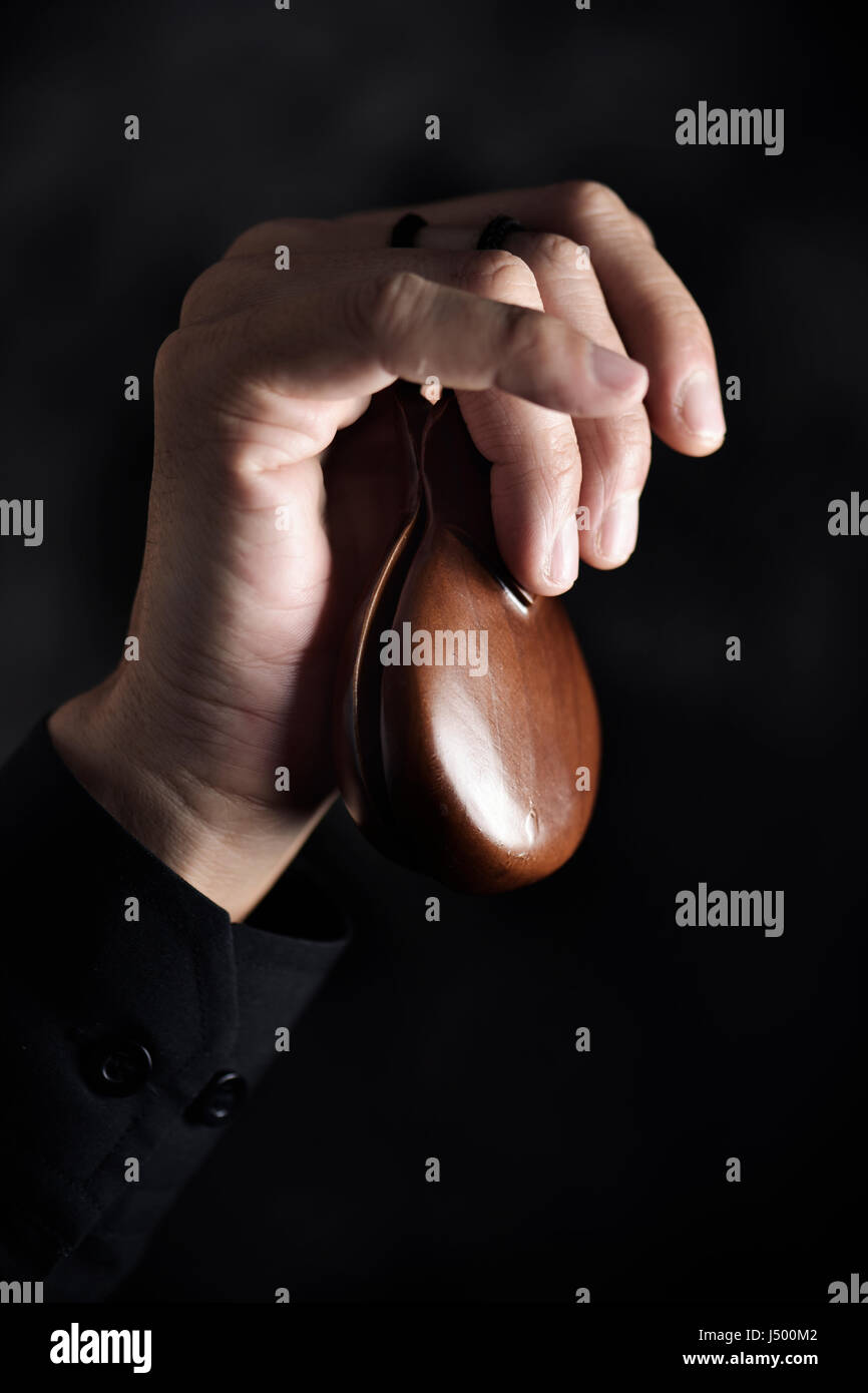 Nahaufnahme der Hand eines kaukasischen Jünglings spielen Kastagnetten vor schwarzem Hintergrund Stockfoto