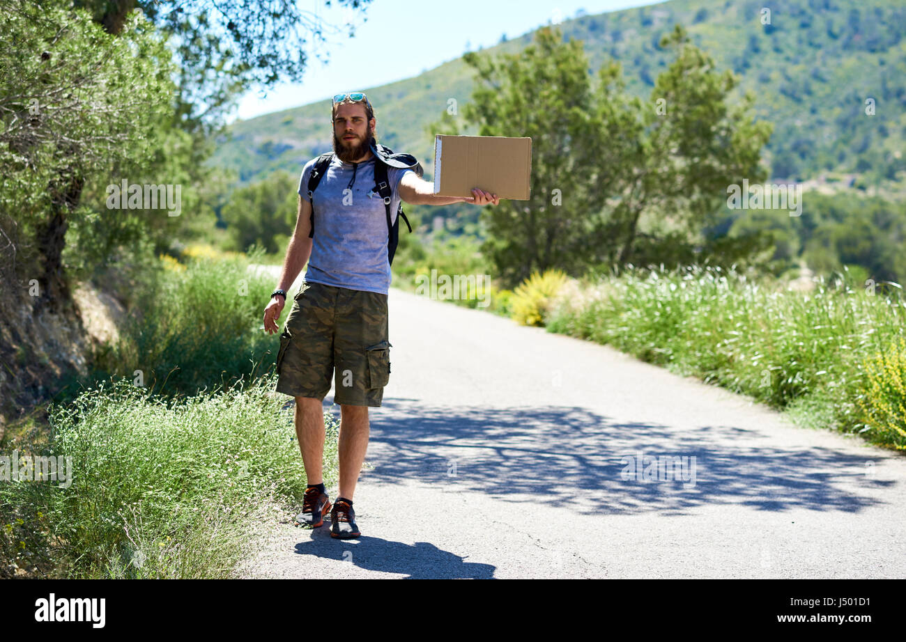 Trampen Reisenden mit einem leeren Pappschild auf einer Bergstraße. Billig reisen. Auto-Stopp Stockfoto