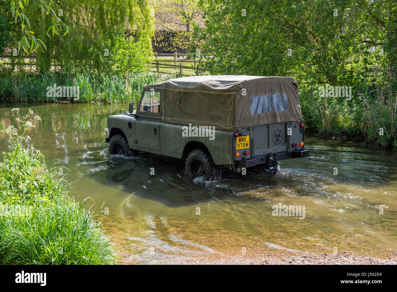 Modell veröffentlicht Bild eines Mannes treiben ein 1973 ex Armee Land Rover Serie 3 langen Radstand in den Fluss VER bildet eine Furt bei Redbournbury, Herts. Stockfoto