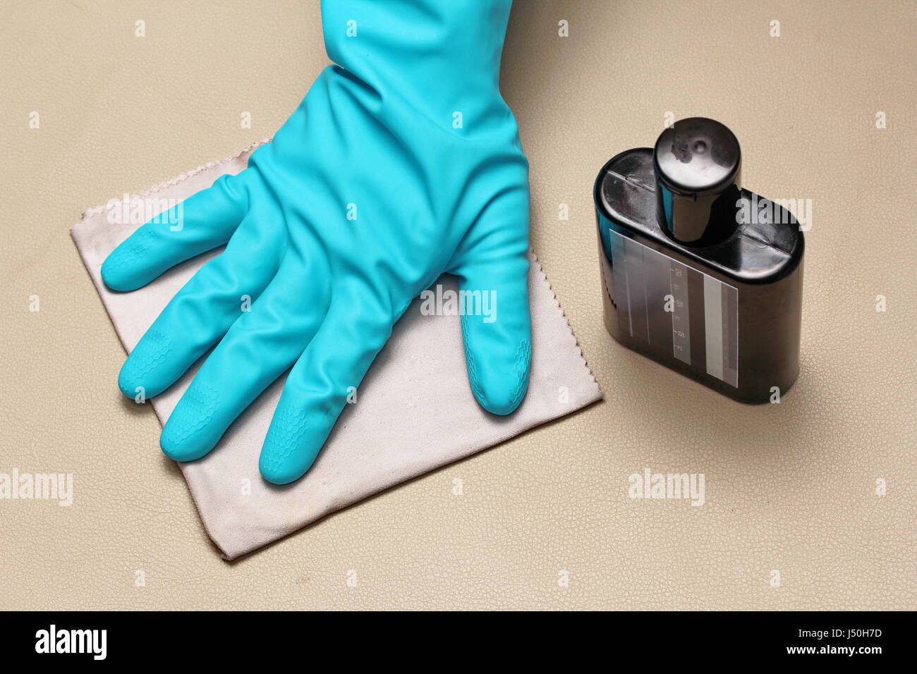 Tragen Sie Gummihandschuhe und rieb sauber Lederwaren durch Chemisches Polieren mit einem Mikrofasertuch. Stockfoto