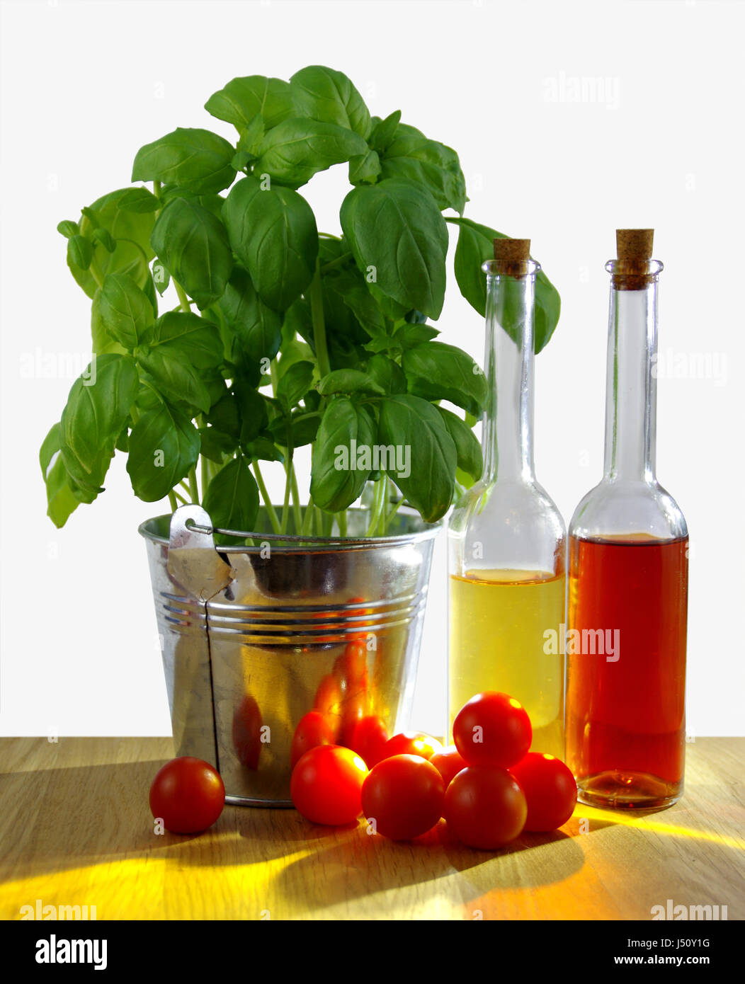 Schichtbildung Basilikum in Blecheimer mit frischen Tomaten und Olivenöl Flasche am Tisch, sonnigen Hintergrundbeleuchtung Stockfoto
