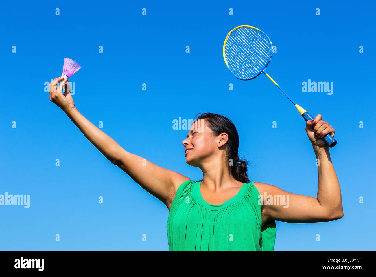 Kolumbianische Frau dienen mit Badminton-Schläger und Shuttle gegen blauen Himmel Stockfoto