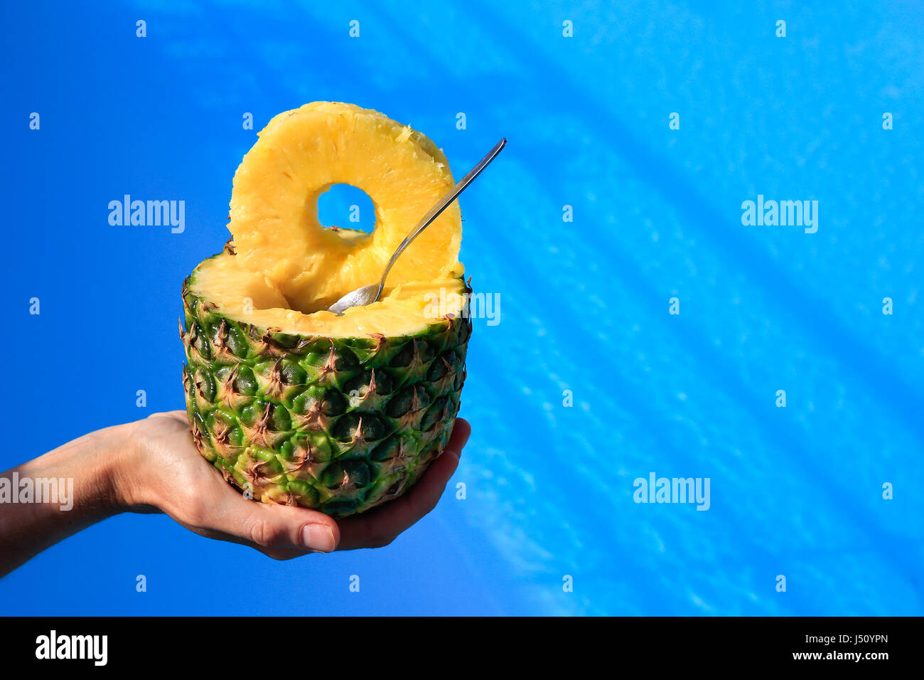 Hand mit frischer Ananas oben blau Wasser schwimmen Stockfoto