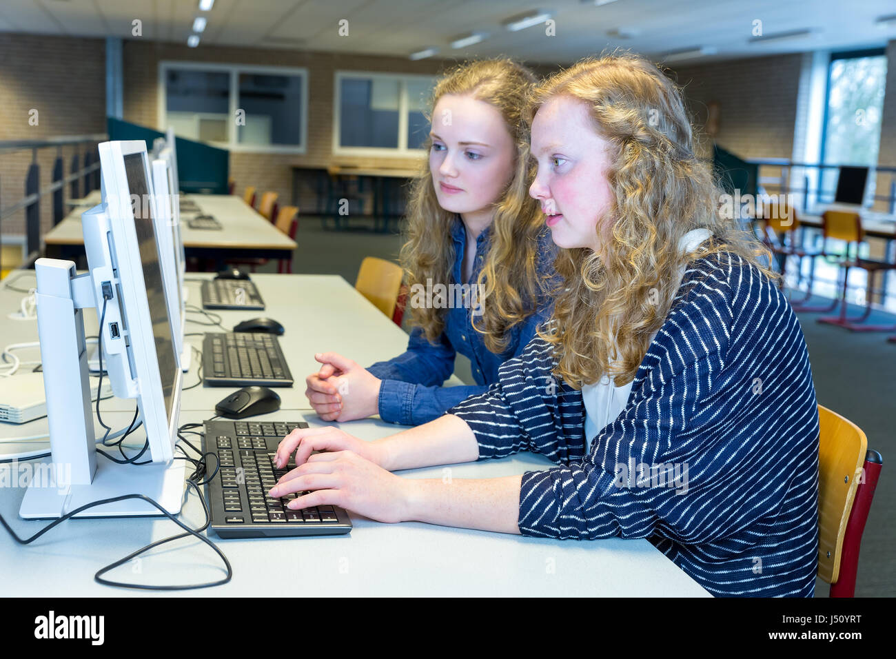 Zwei kaukasische Mädchen arbeiten am Computer im Arbeitszimmer der High school Stockfoto