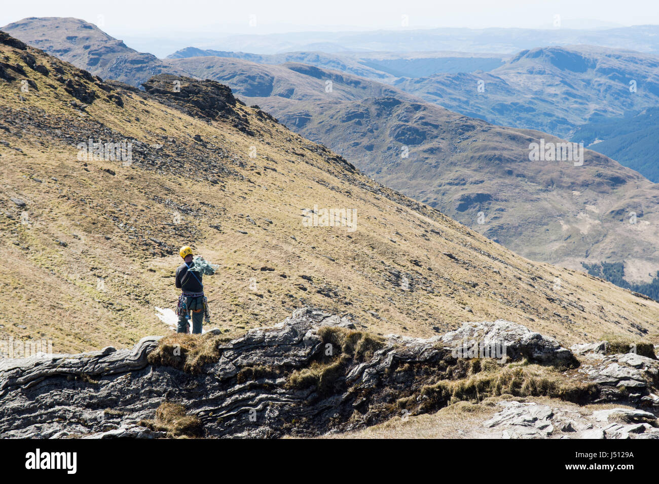 Ein Kletterer erreicht den Gipfel der Felsen auf Ben Artair, "Der Schuster", ein beliebter Berg zum Klettern in den westlichen Highlands von Schottland. Stockfoto