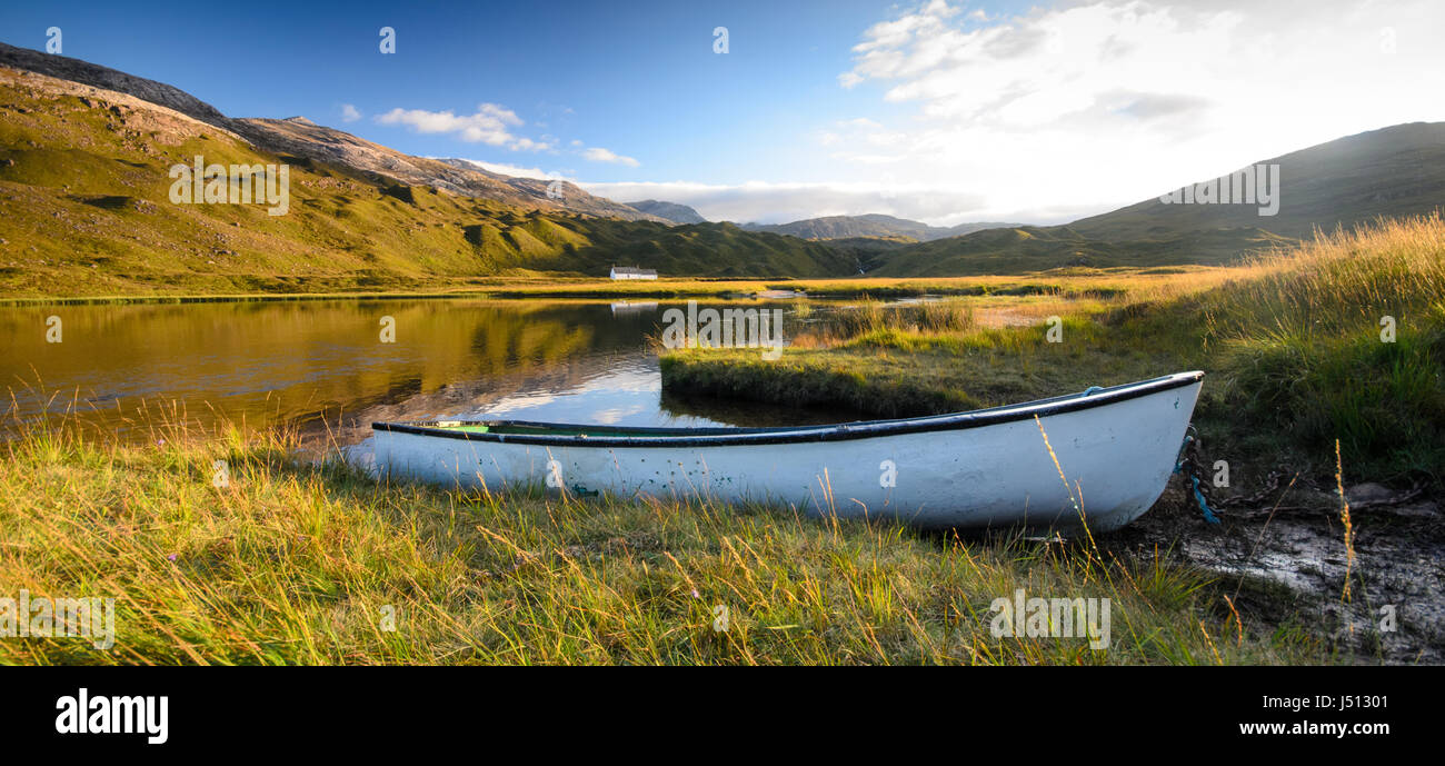 Ein kleines Ruderboot am Ufer des man ein Iasgair See in der Talsohle von Glen Torridon, unter den Torridon Hills Bergen von West e Stockfoto