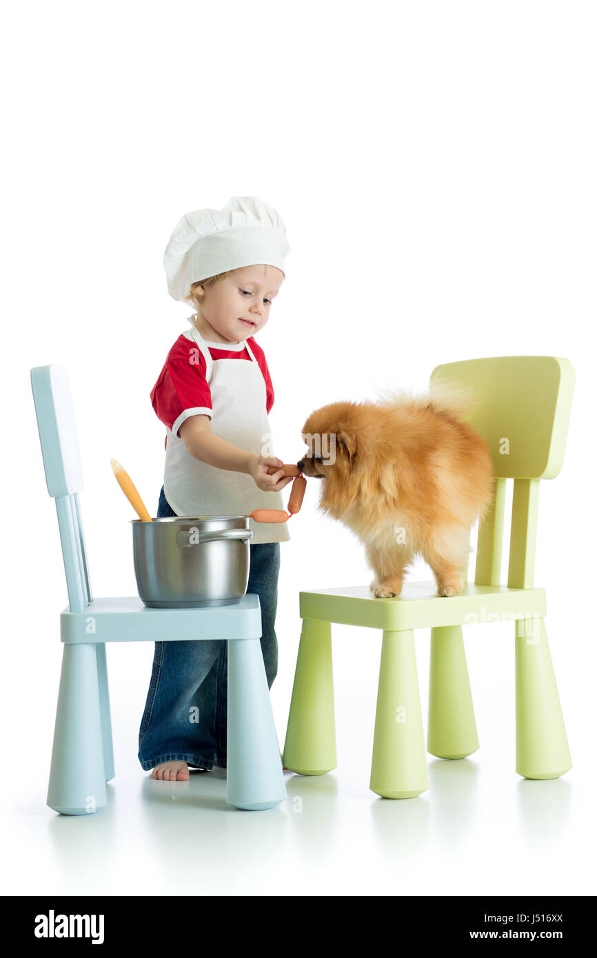 Role-playing Game. Kind Junge spielt Koch mit Haustier. Kind weared Koch füttert Hund. Stockfoto