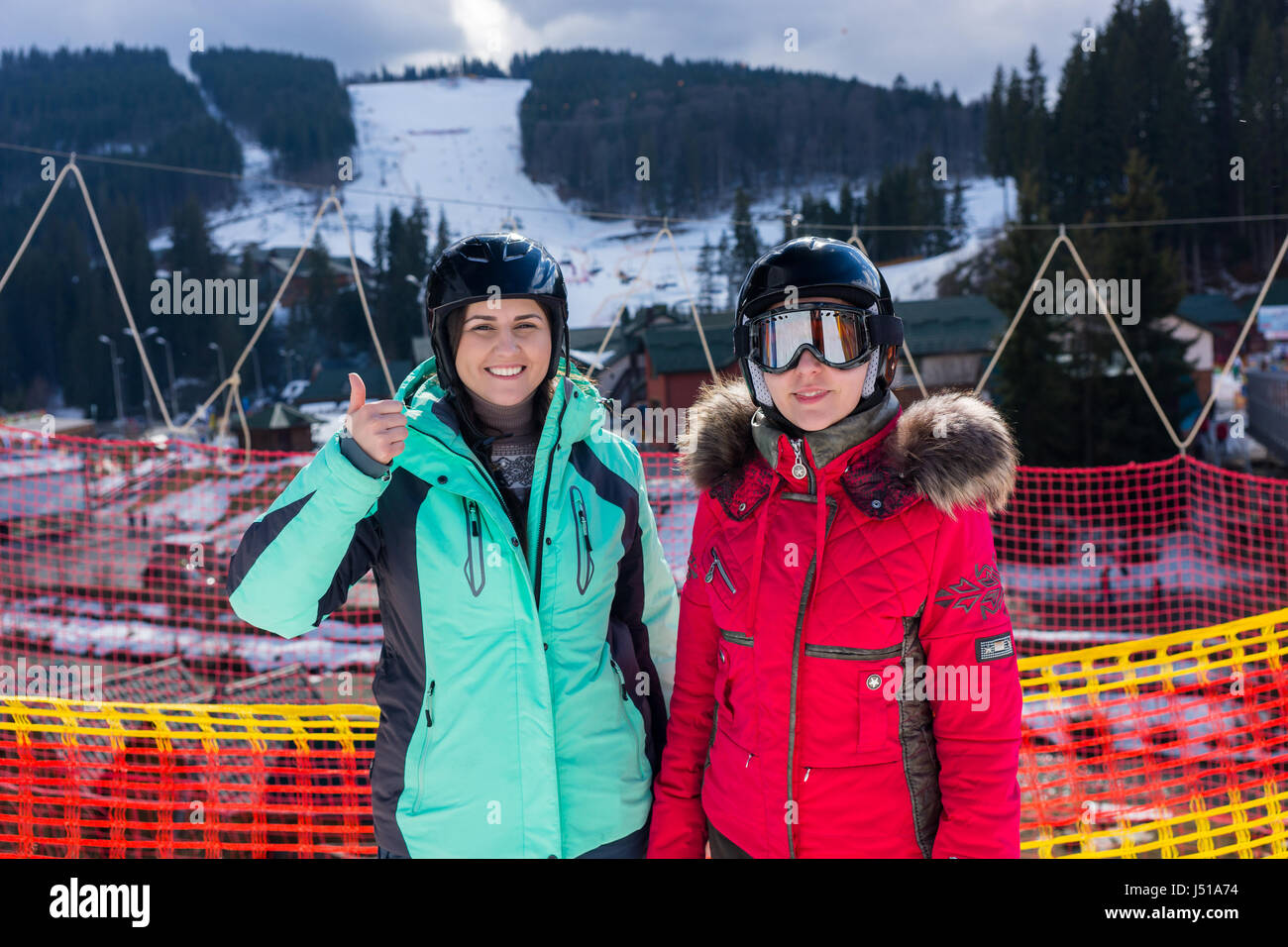 Junge, lächelnde Frauen in Ski Anzüge, mit Helmen und Skibrille stehend in einem Skigebiet im Winter Stockfoto