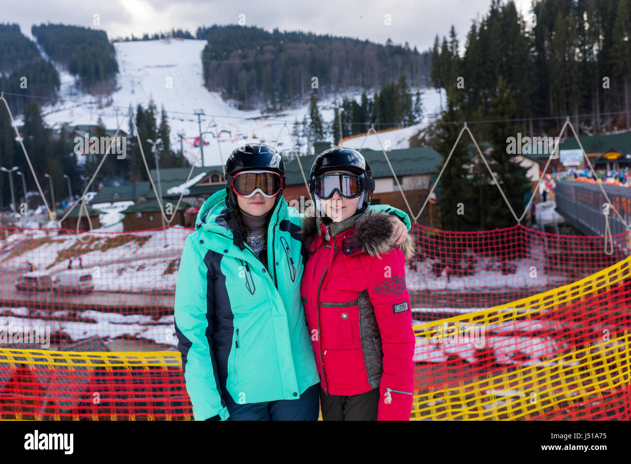 Lächelnde Frauen in Skianzüge, mit Helmen und Ski goggles stehend in einem Skigebiet im Winter Stockfoto