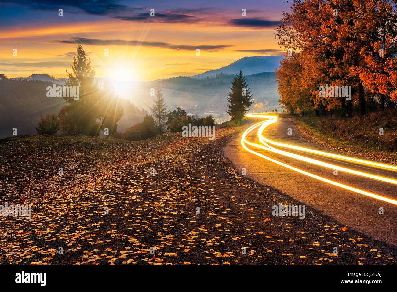 Landschaft Straße Autoscheinwerfer. schöne herbstliche Berglandschaft bei Sonnenuntergang Stockfoto