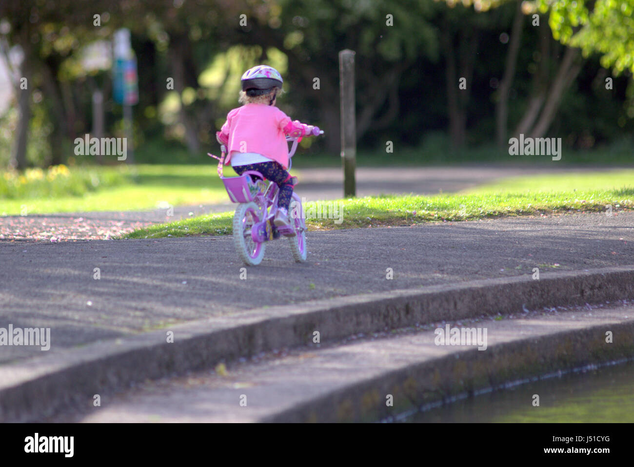 kleines Mädchen mit rosa Fahrrad in Knightswood Parken Glasgow Stockfoto