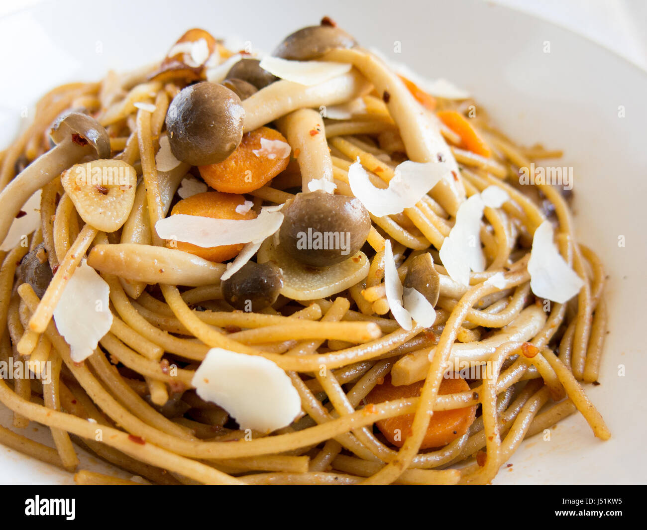 Pikante Spaghetti mit Shimeiji Pilzen, Karotte, Chili-Flocken und Knoblauch mit Parmesan-Käse auf weißen Teller rasiert Stockfoto