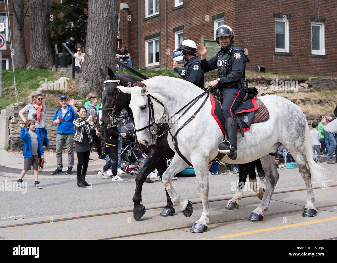 Toronto berittene Polizei Offiziere Welle für die Zuschauer entlang der Queen Street East, während die Strände Easter Parade 2017 Stockfoto