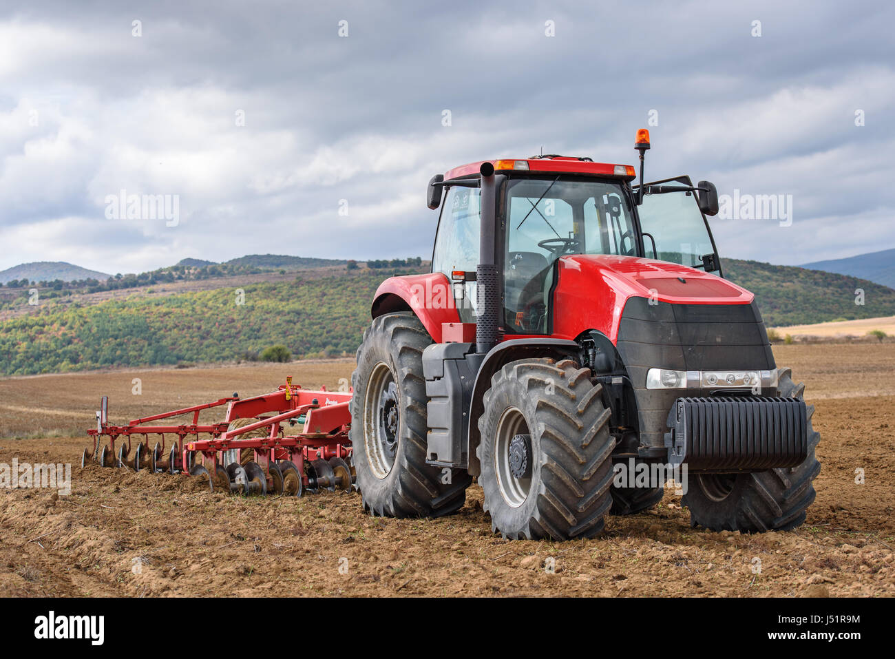Bauer im Traktor vorbereiten Farmland für Saatbeet. Stockfoto