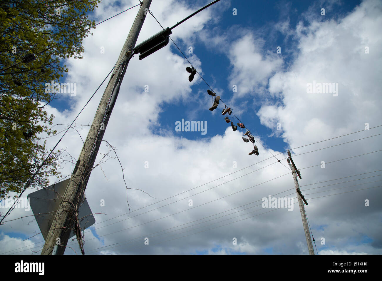 Schuhe und Stiefel aufgereiht auf einem elektrischen Draht über eine Landstraße. Stockfoto