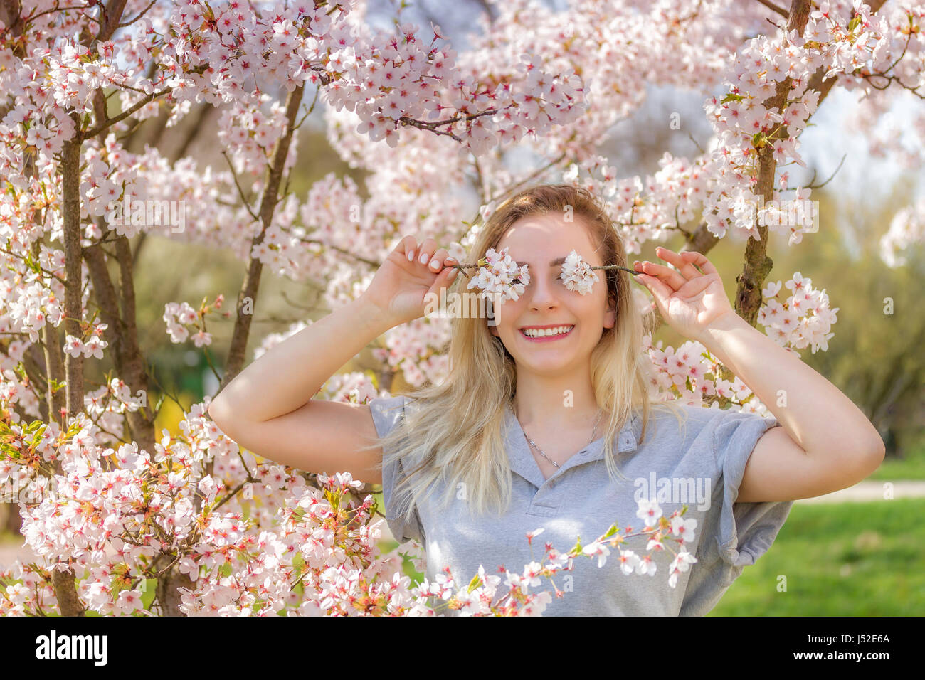 Junge Frau ihre Augen mit frischen bunten Blumen bedecken. Stockfoto