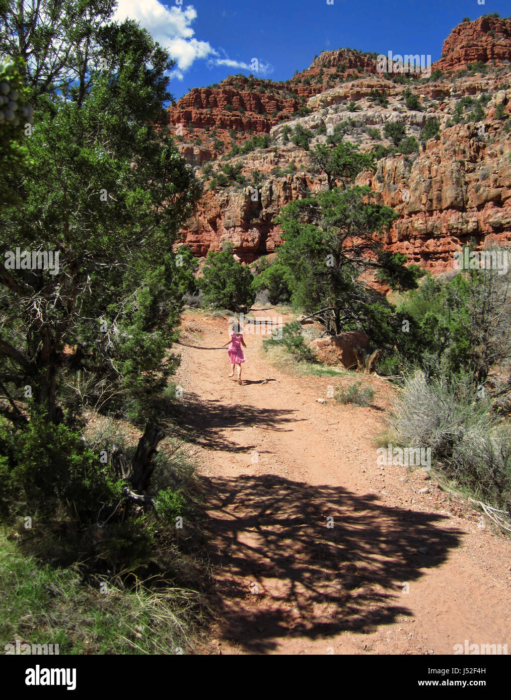 Mädchen laufen auf einem Pfad in der Nähe von roten Sandsteinfelsen in Utah. Stockfoto