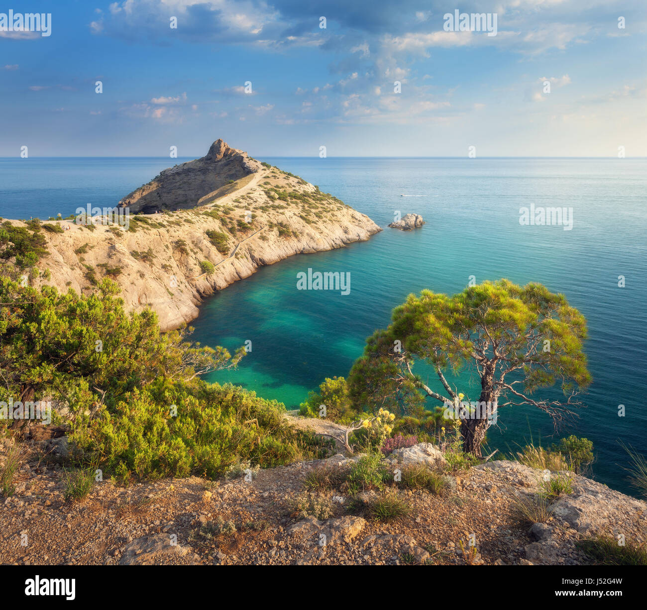 Herrliche Aussicht auf den grünen Baum, Berge, Meer mit türkisfarbenem Wasser und bunten blauen Himmel bei Sonnenaufgang. Sommerlandschaft in Bergen am Meeresstrand Stockfoto