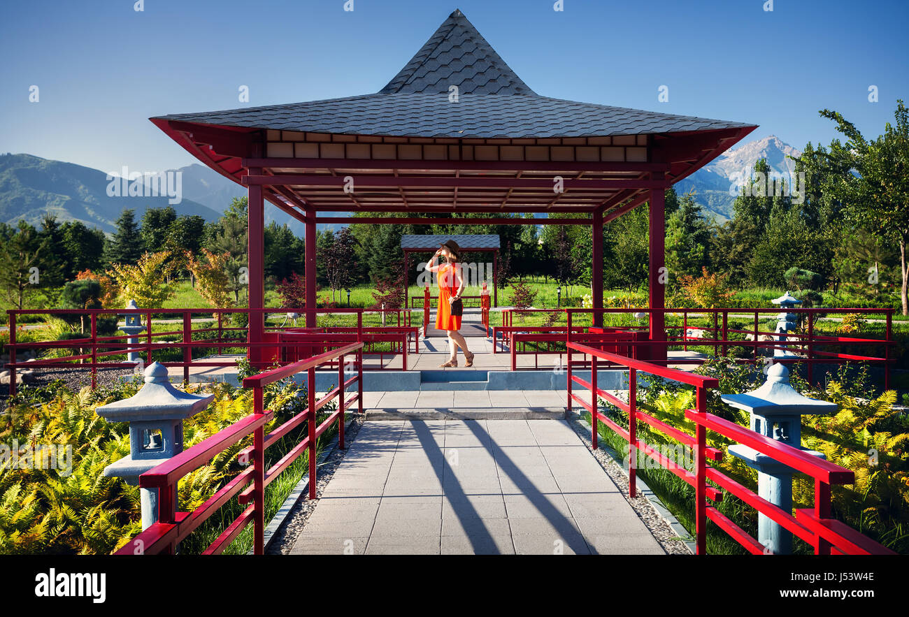 Frau in orange Kleid und Hut in der Pagode am japanischen Garten Stockfoto