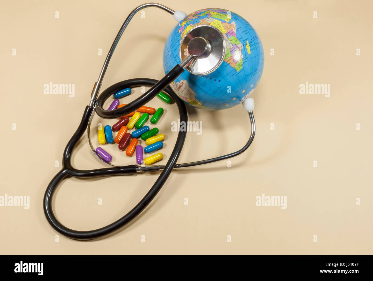 Sphärische Weltkarte platziert zwischen den Armen des medizinische Stethoskop mit farbigen Pillen Konzeptbild über Rettung und Heilung der Erde Stockfoto