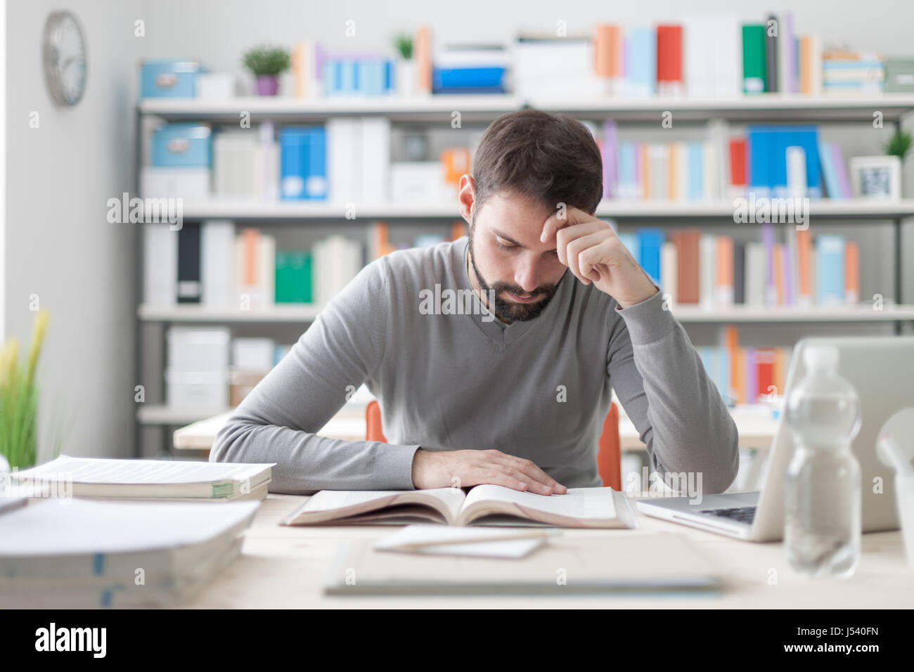Erwachsener Mann am Schreibtisch sitzen und studieren an der Bibliothek konzentriert lernen und selbst-Verbesserung-Konzept Stockfoto