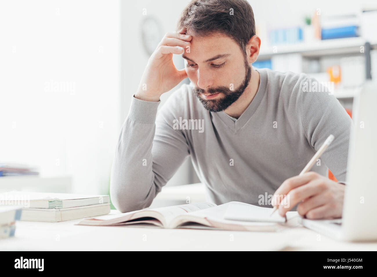 Erwachsener Mann am Schreibtisch sitzen und studieren an der Bibliothek konzentriert lernen und selbst-Verbesserung-Konzept Stockfoto