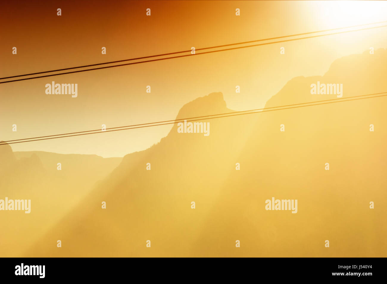 Blick auf die untergehende Sonne und Sonnenstrahlen über nebligen Bergen Stockfoto