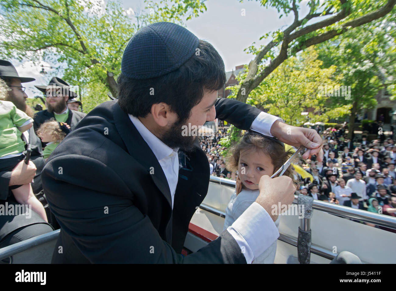 5.14.2017 bekommt ein orthodoxen jüdischen Jungen seinen ersten Haarschnitt an Alter drei bei der Verzögerung B'Omer Parade in Crown Heights, Brooklyn, New York City Stockfoto