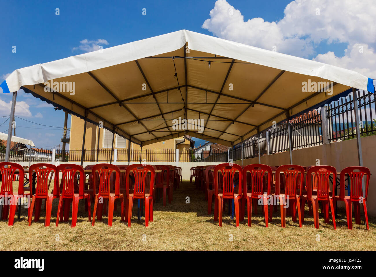 weißen Festzelte mit roten Plastikstühle im Garten Stockfoto