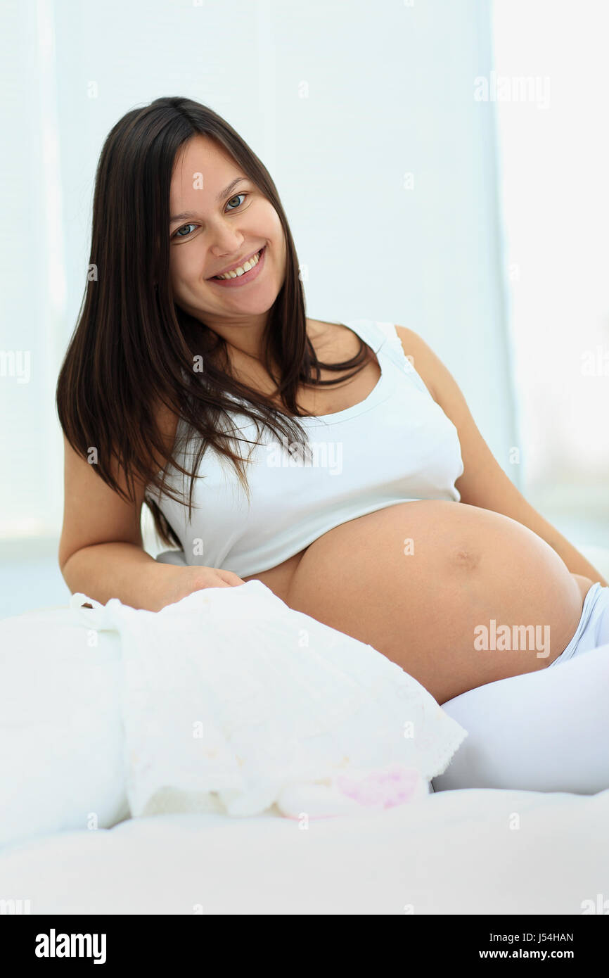 Glückliche Schwangerschaft sitzt auf dem Sofa zu Hause im Schlafzimmer Stockfoto