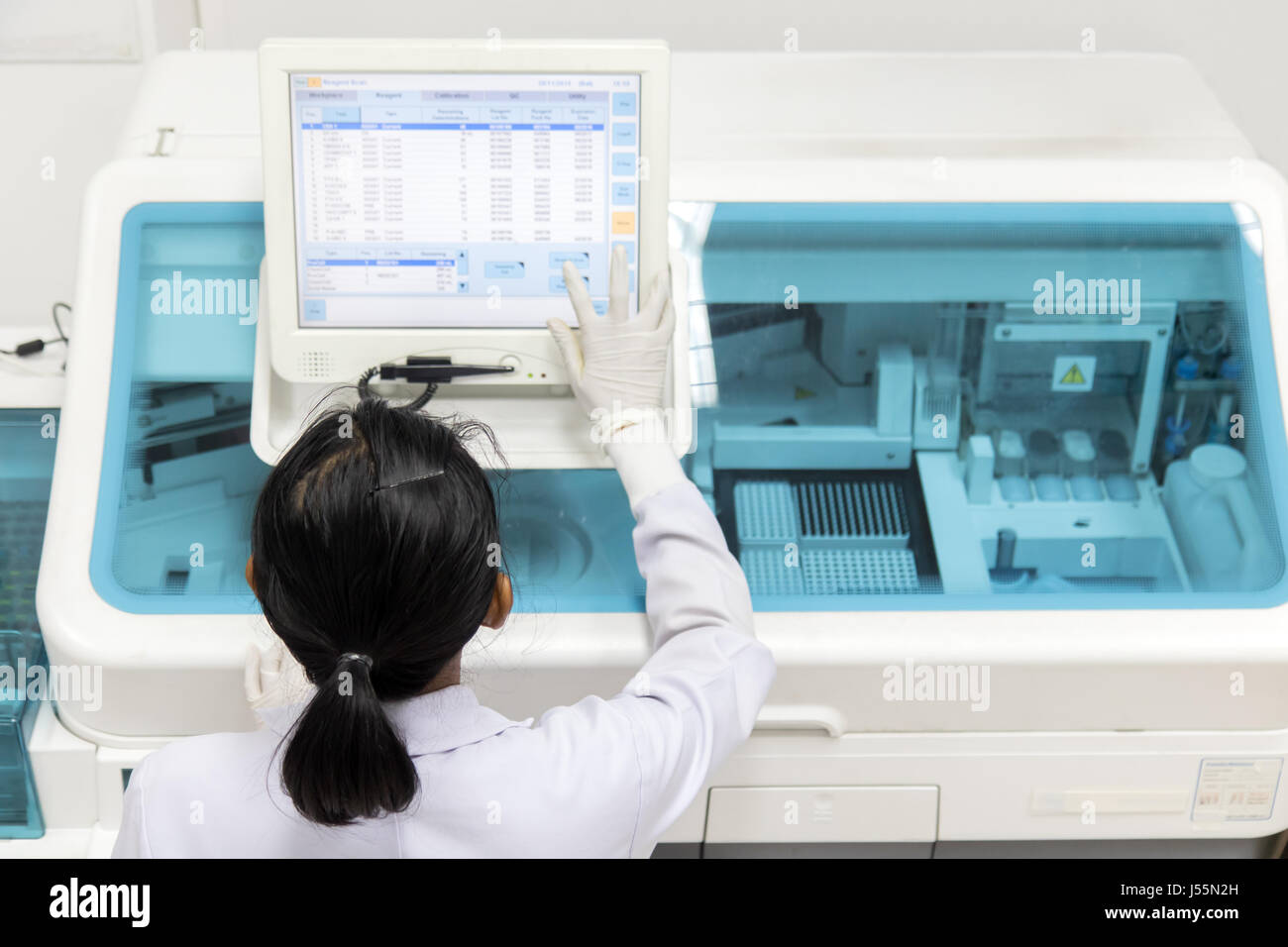 Frau arbeitet in einem Labor auf einem modernen Rechner für Bluttests. Arzt überprüft das Blut der Patienten. Stockfoto