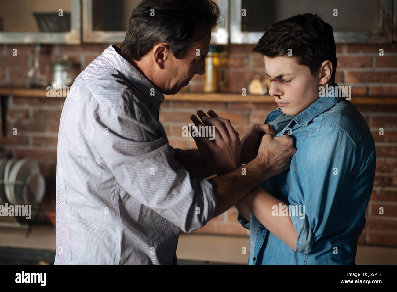 Strengen Vater Beschlagnahme Shirt seines Sohnes Stockfoto