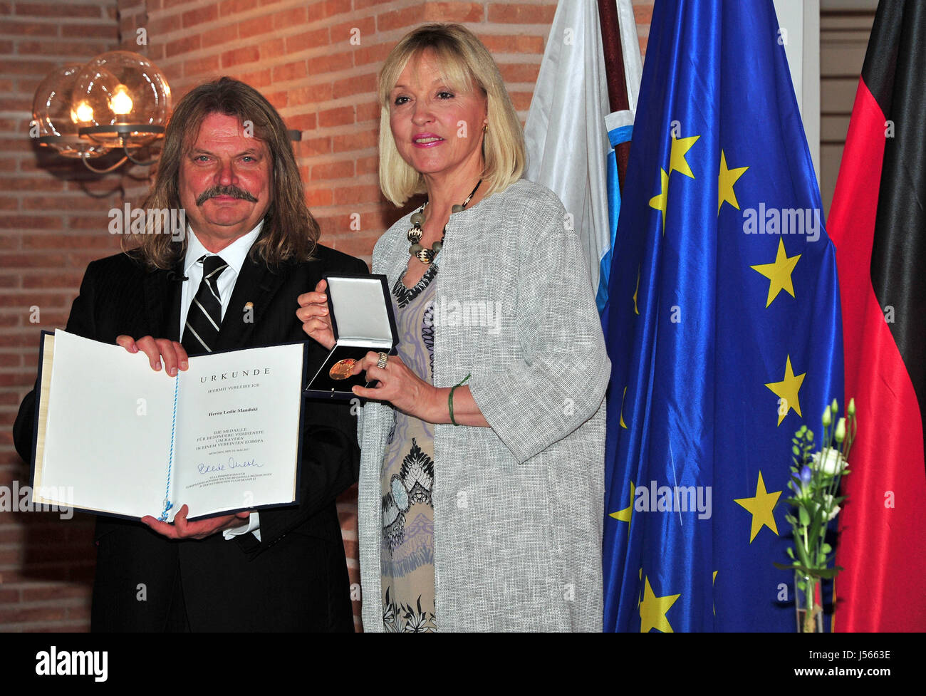 München, Deutschland. 16. Mai 2017. Deutsch-ungarische Musiker und Komponist Leslie Mandoki (L) präsentiert die bayerische Europa-Medaille, auch bekannt als die Medaille für außerordentliche Verdienste um Bayern in einem Vereinten Europa vom Bayerischen Staatsminister für europäische Angelegenheiten und internationale Beziehungen Beate Merk im Prinz Carl Palais in München, Deutschland, 16. Mai 2017. Foto: Ursula Düren/Dpa/Alamy Live News Stockfoto
