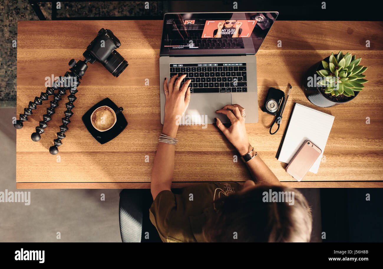 Draufsicht der weiblichen Vloggerin Videobearbeitung auf Laptop. Junge Frau auf Computer mit Kaffee und Kameras auf Tisch arbeiten. Stockfoto
