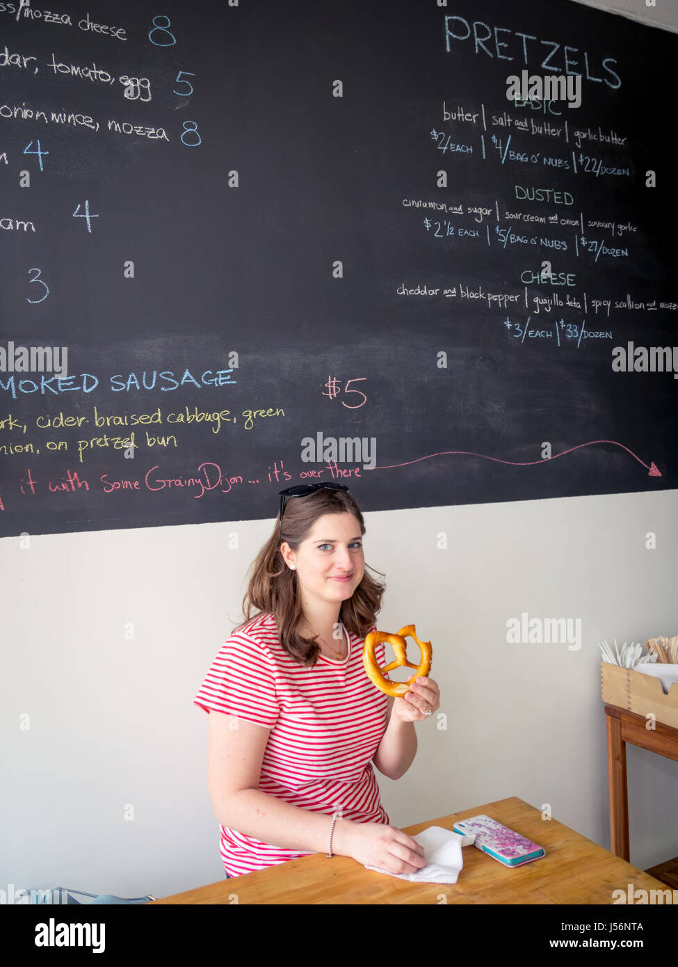 Eine hübsche Brünette Mädchen hält eine Salz-und-Butter-weiche Brezel von Zwicks Brezeln in Edmonton, Alberta, Kanada. Stockfoto