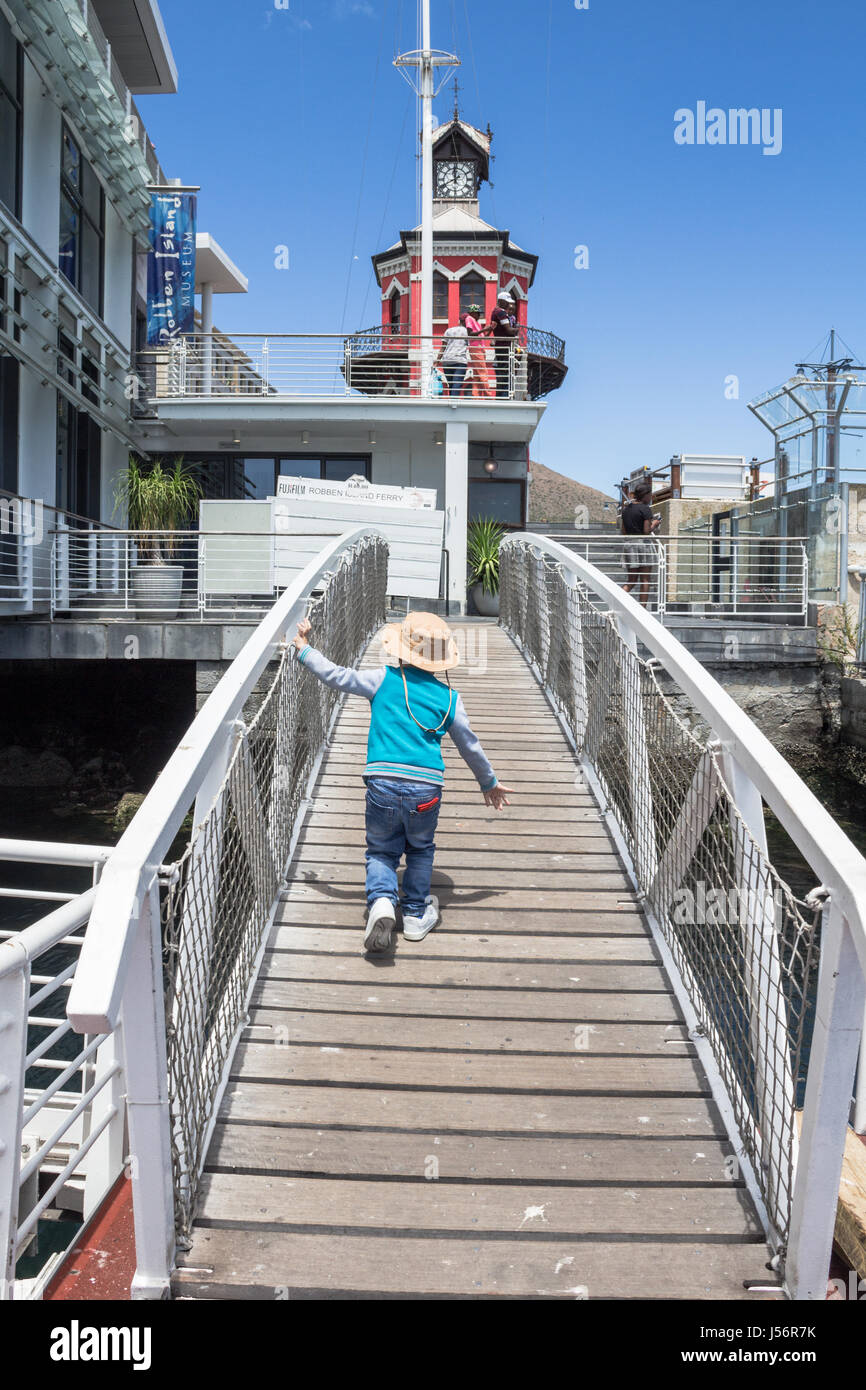 CAPE TOWN, SOUTH AFRICA - 19. Dezember 2017: aufgeregt kleiner Junge läuft auf der Nelson Mandela Gateway Bridge auf V & A Waterfront Kapstadt vor boardin Stockfoto