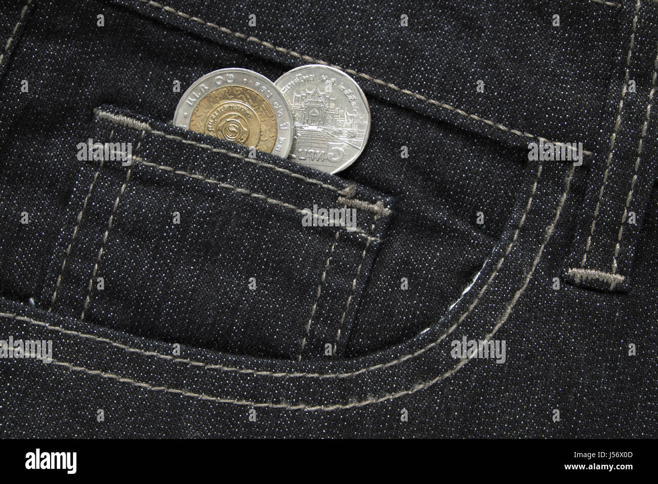 Thai bath Münzen ragte aus der schwarzen Jeans-Tasche. Hautnah. Stockfoto