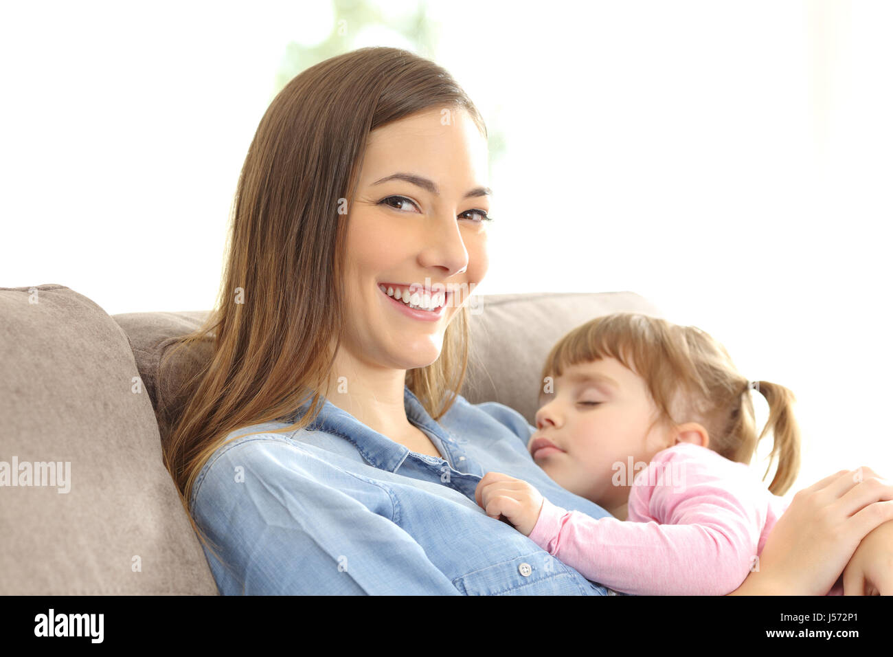 Mutter sah Sie mit ihrer Tochter über ihre Brust sitzt auf einer Couch zu Hause schlafen Stockfoto