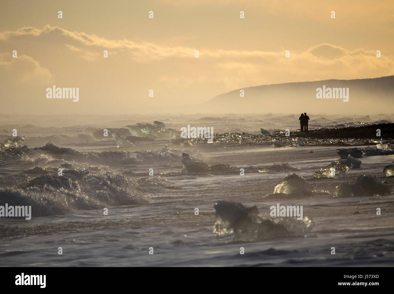 Zwei Personen genießen den Sonnenuntergang im Diamond Beach in der Nähe der Gletscherlagune in Süd-Ost-Island Stockfoto